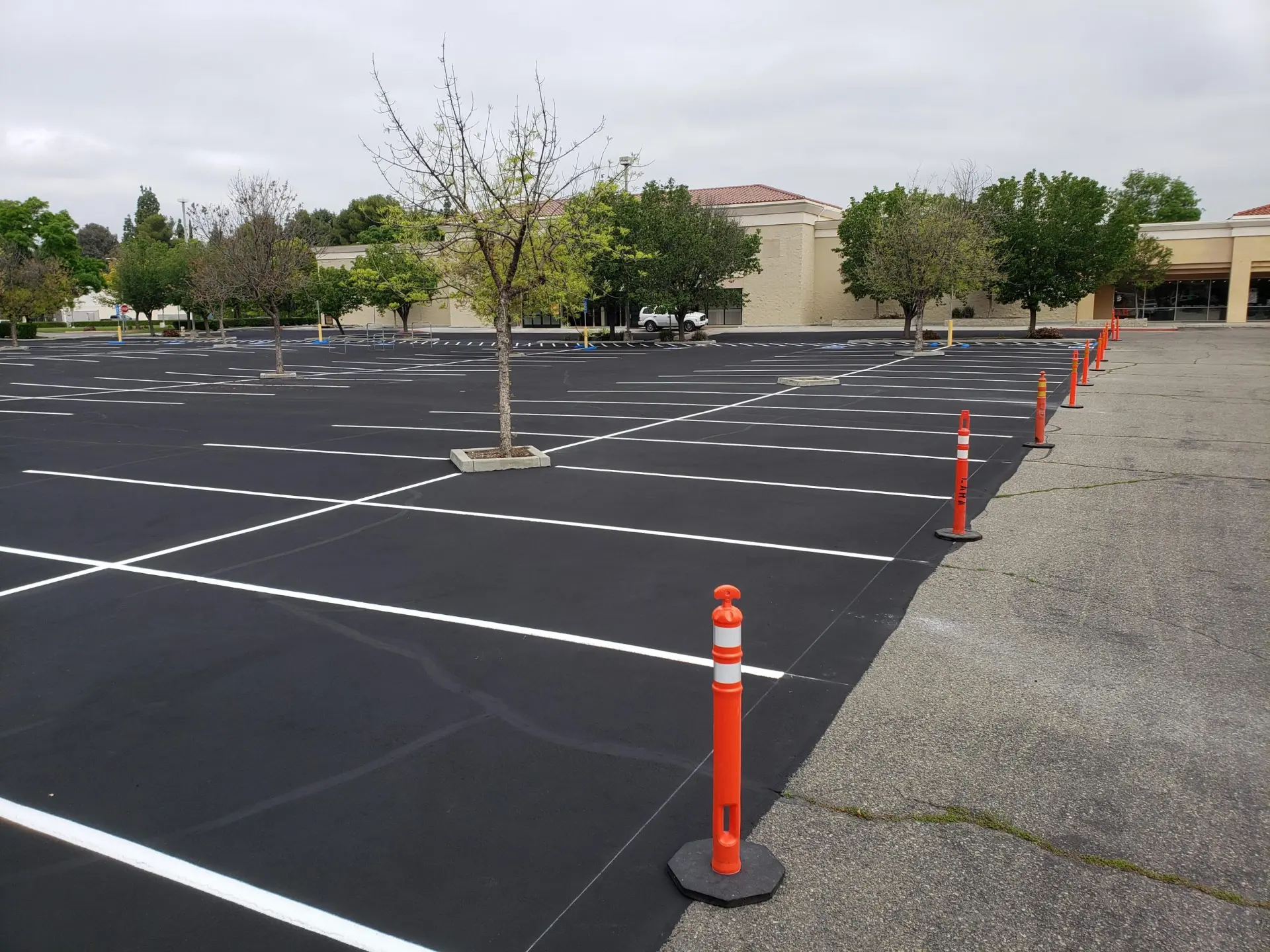 Freshly sealcoated commercial parking lot with new striping and safety delineators in Visalia, CA