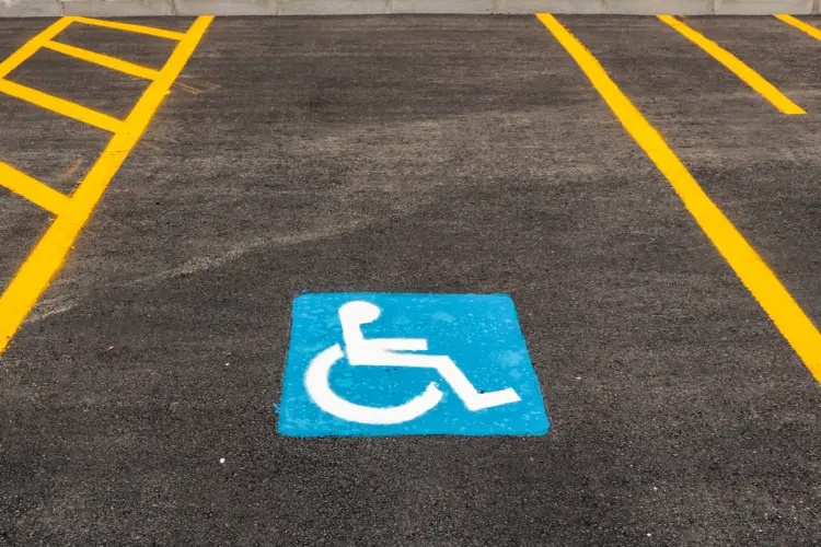 Handicap accessible parking space with blue and white wheelchair symbol painted on asphalt, flanked by yellow striping