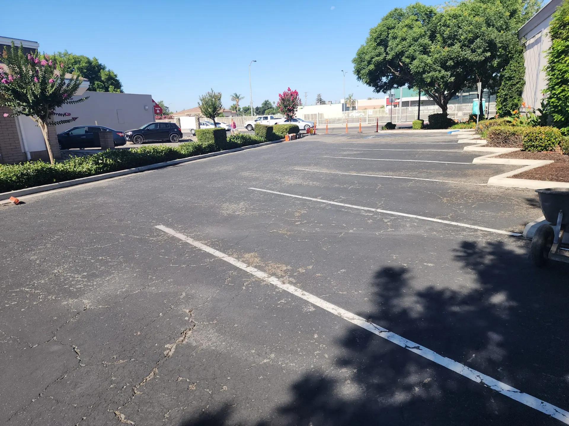 Deteriorated commercial parking lot before repaving, showing cracked and faded asphalt with worn, chipped white parking lines