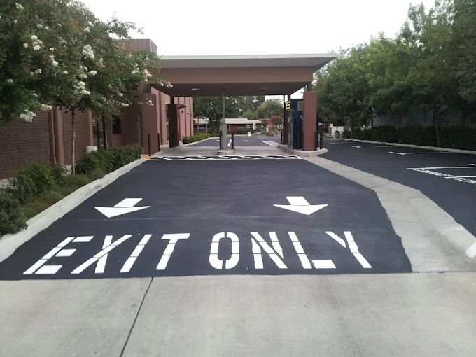 Exit Only stenciled pavement markings with directional arrows at commercial driveway