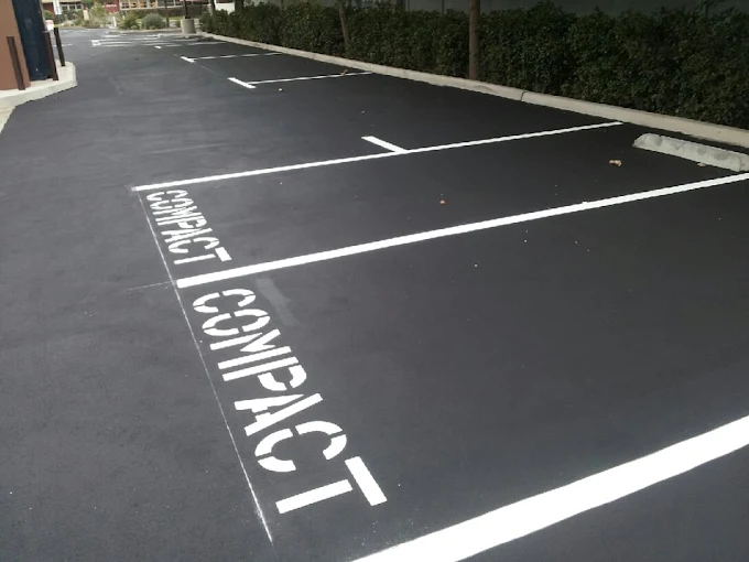 Compact parking space striping with stenciled lettering in commercial parking lot