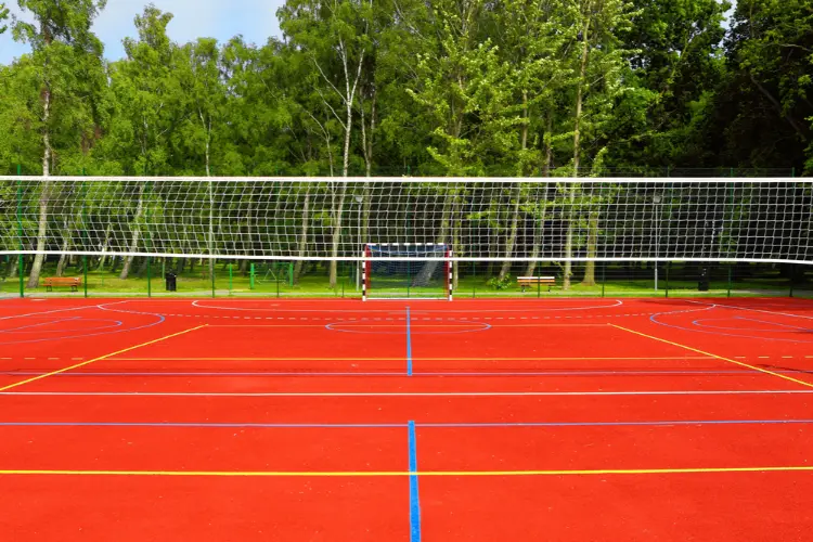 Multi-sport court with red surface and painted volleyball, futsal, and boundary lines